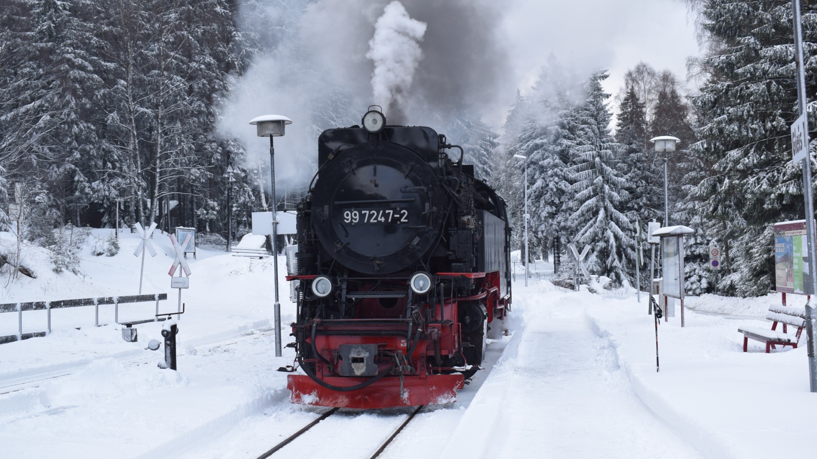 Старый локомотив на заснеженной станции у леса зимой
