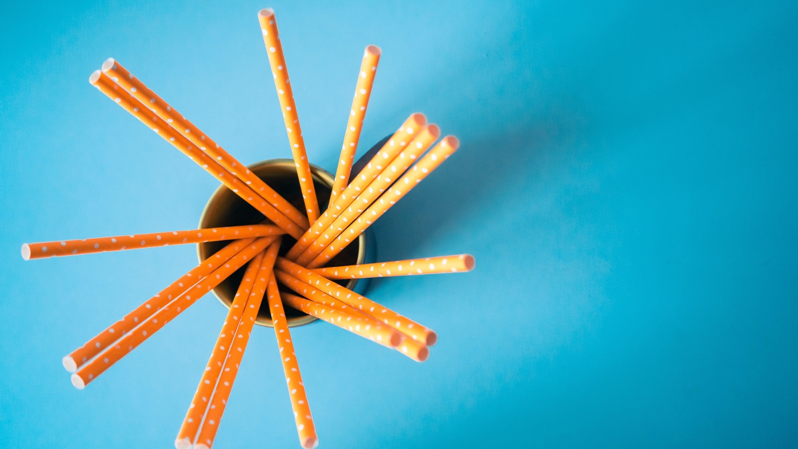 Трубочки в стакане на голубом столе