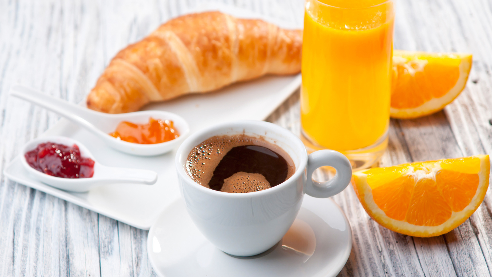 Чашка кофе на столе с соком и круассаном