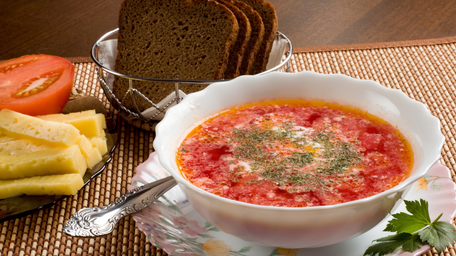 A plate of red borscht on the table with cheese and black bread