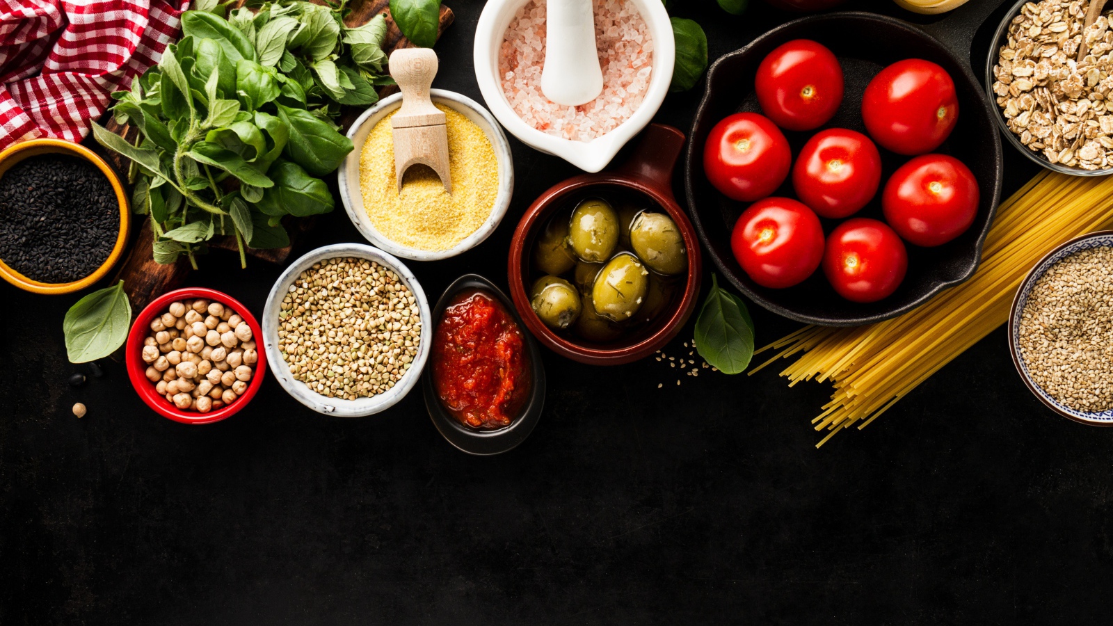 Крупы на столе с зеленью, помидорами, оливками и спагетти