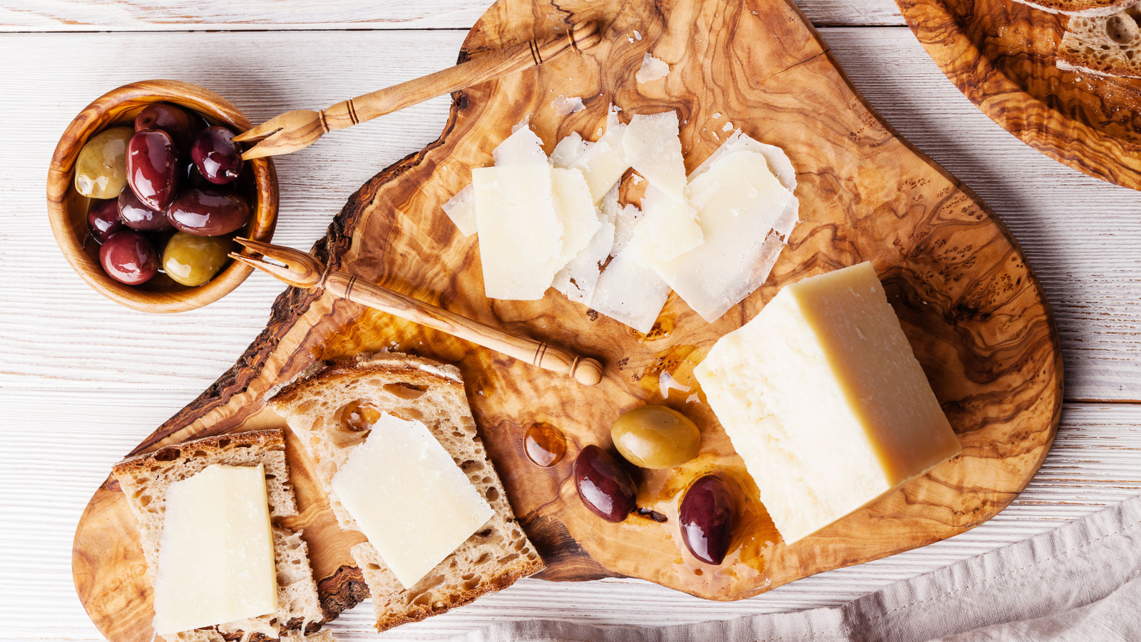 Сыр на доске с хлебом и и оливками