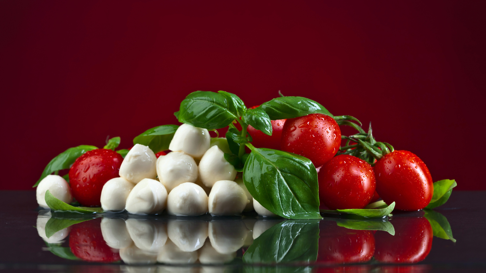 Сыр на столе с зеленью базилика и красными помидорами