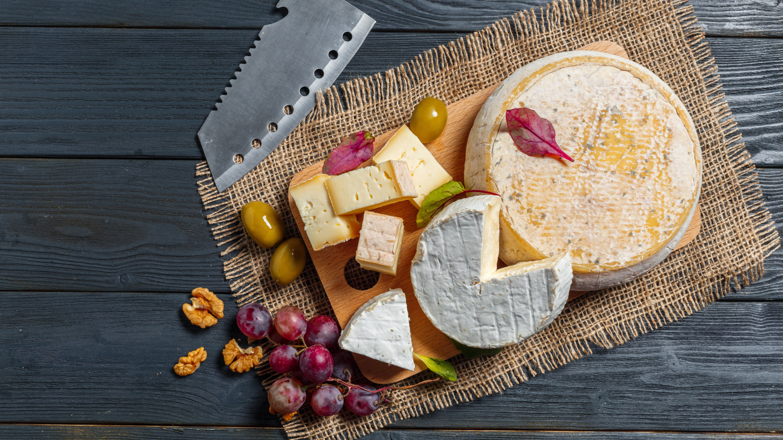 Сыр с плесенью на столе с орехами и виноградом 