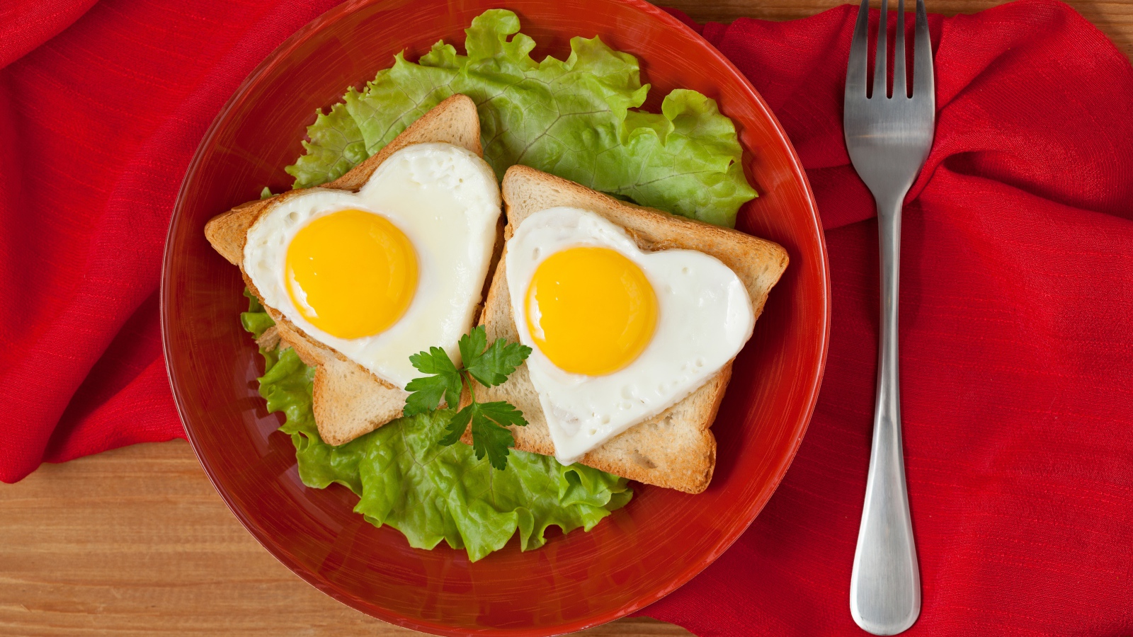 Гренки с яичницей на тарелке с листьями салата 