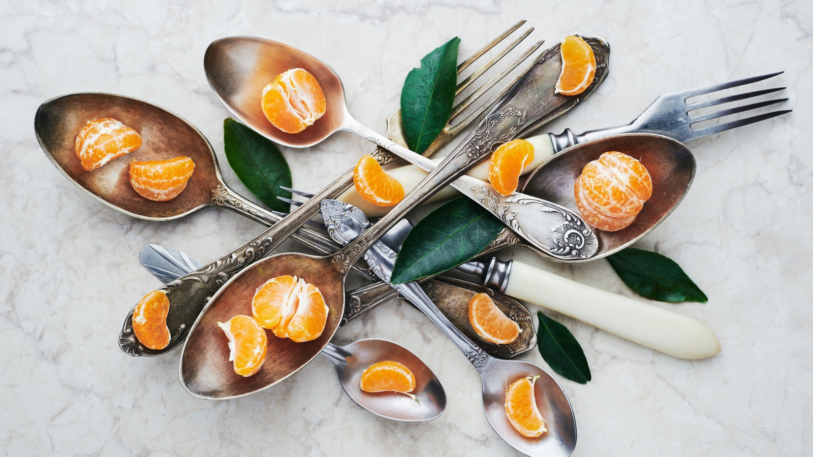 Столовые приборы на столе с дольками мандарина