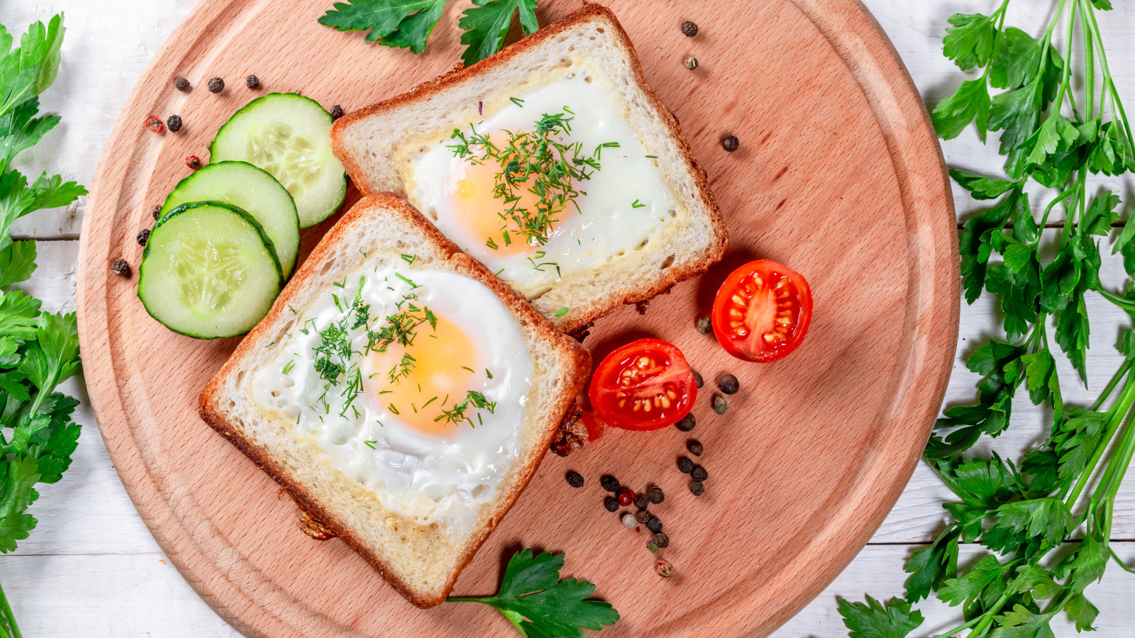 Яичница в хлебе на доске с помидорами, огурцами и петрушкой