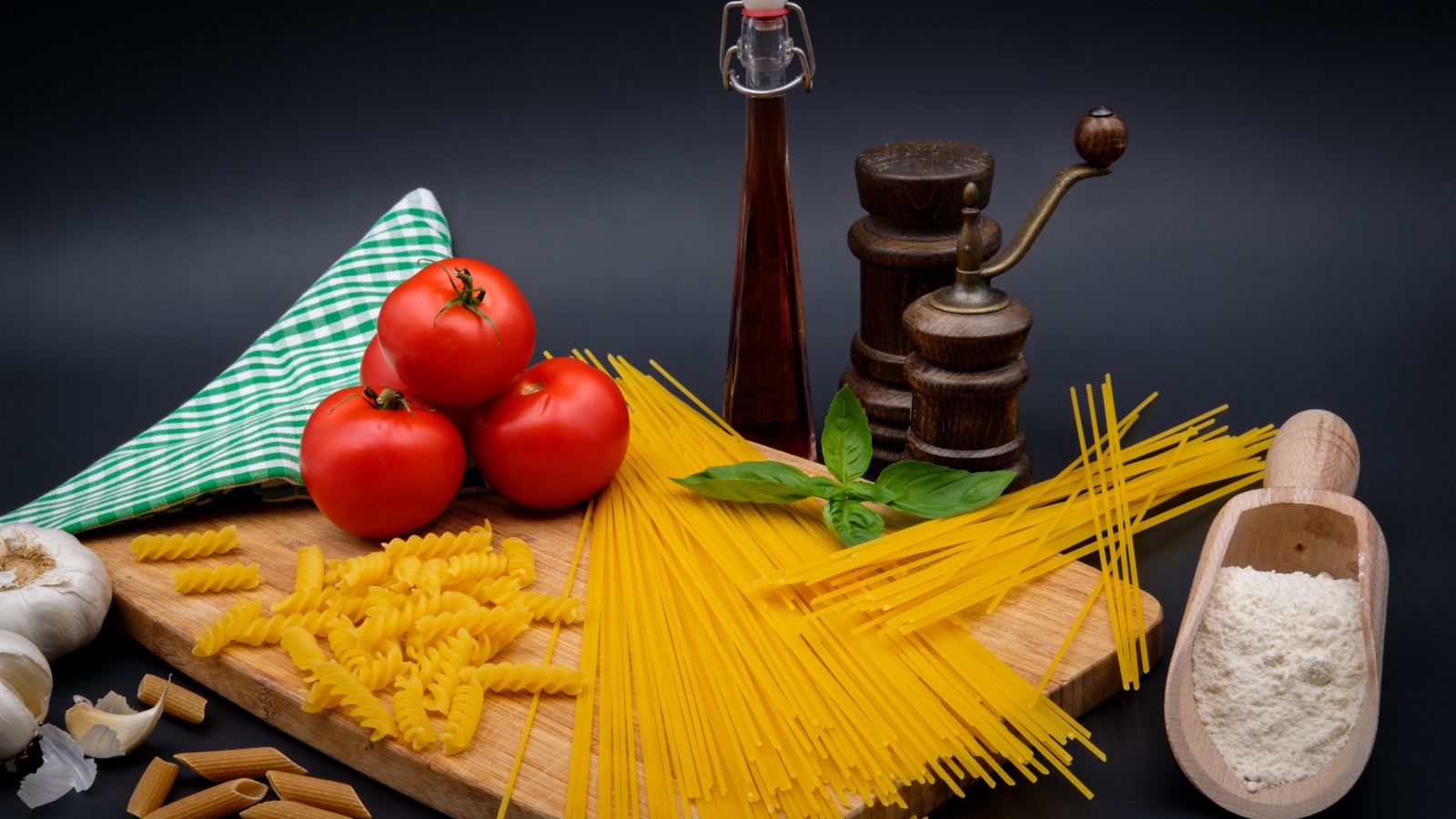 Макаронные изделия на столе с мукой, помидорами и специями