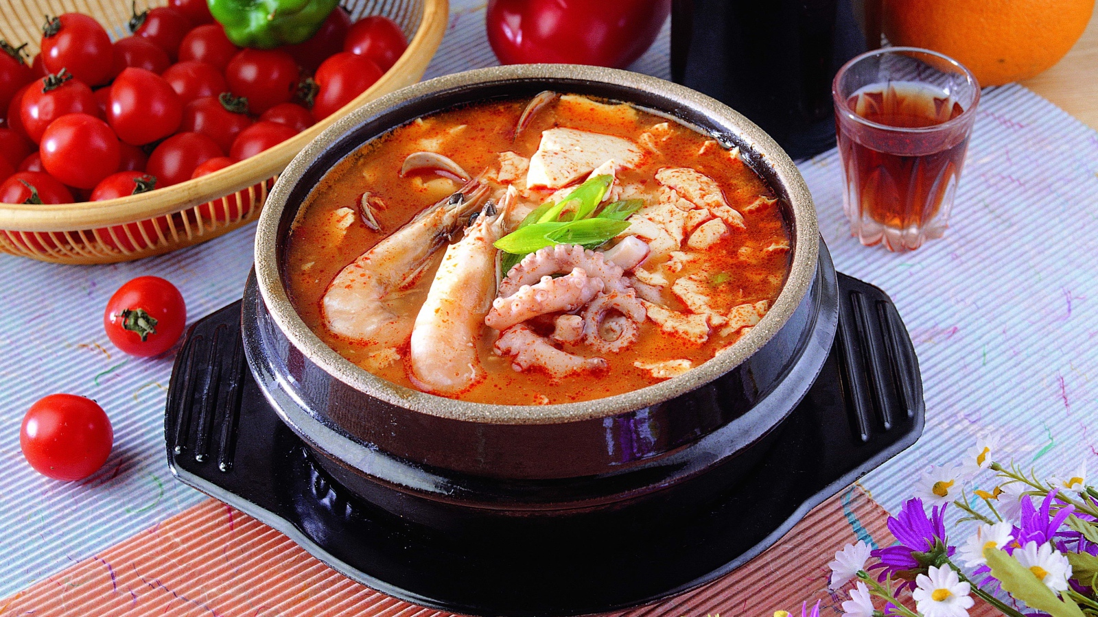 Тарелка красного супа с морепродуктами на столе с овощами 