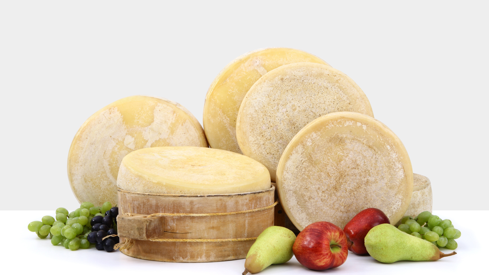 Сыр на столе с грушами, яблоками и виноградом