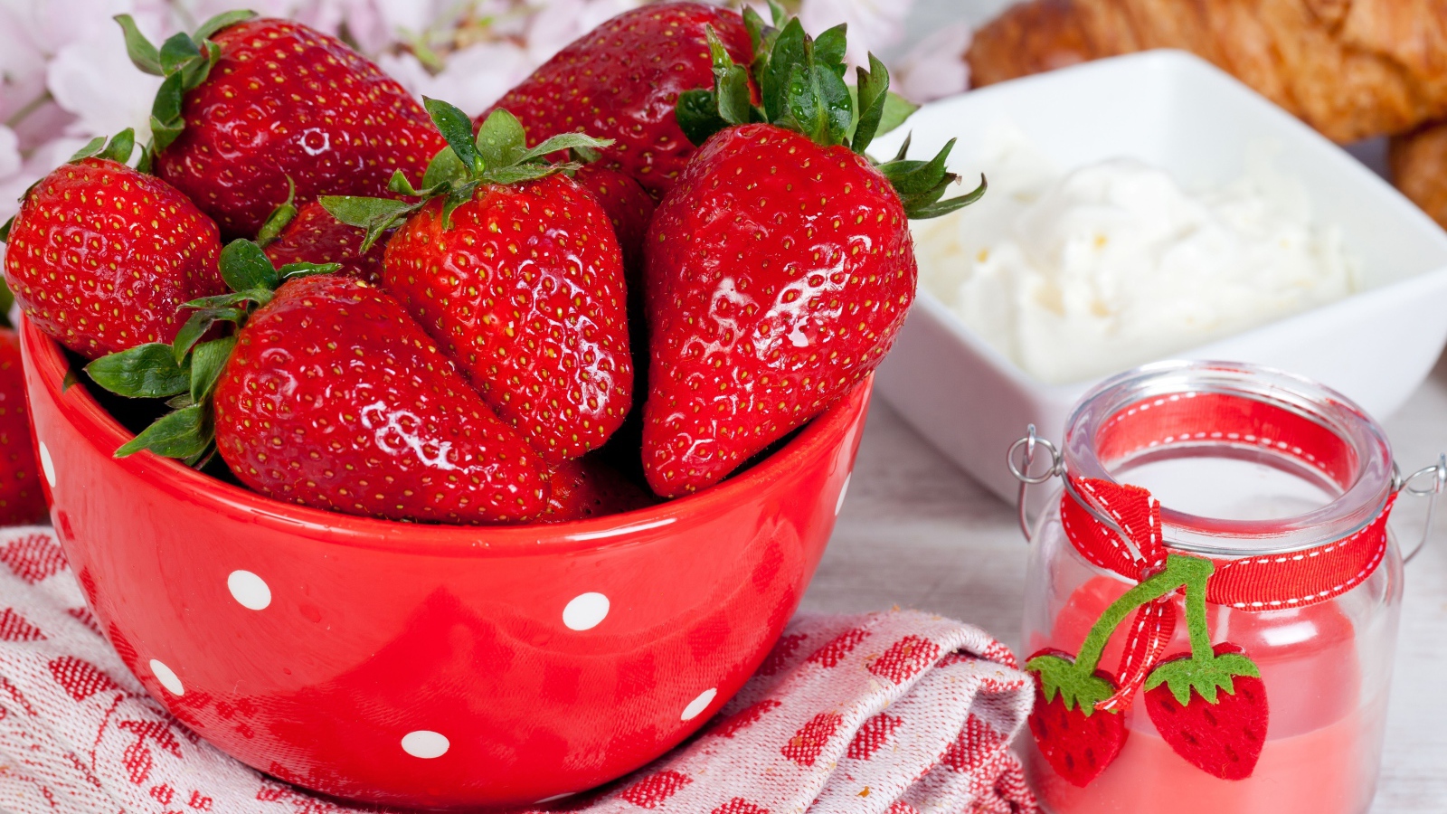 Свежие ягоды клубники в красной миске на столе