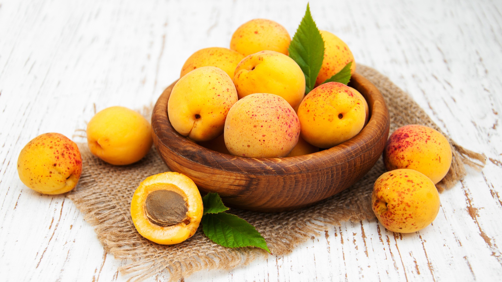 Спелые абрикосы в деревянной миске на столе