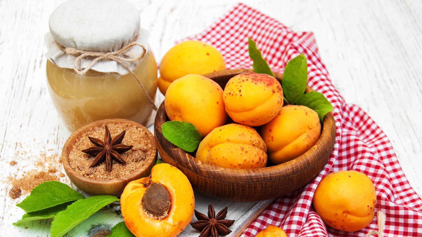 Спелые абрикосы на столе с бадьяном, коричневым сахаром и джемом
