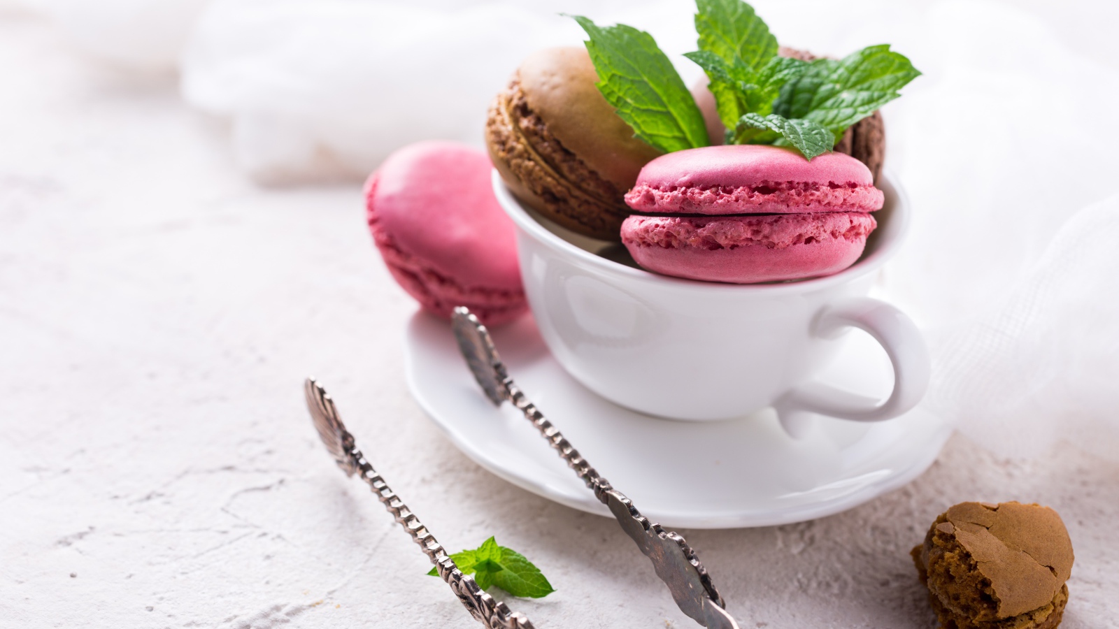 Разноцветный десерт макарун в белой чашке на столе