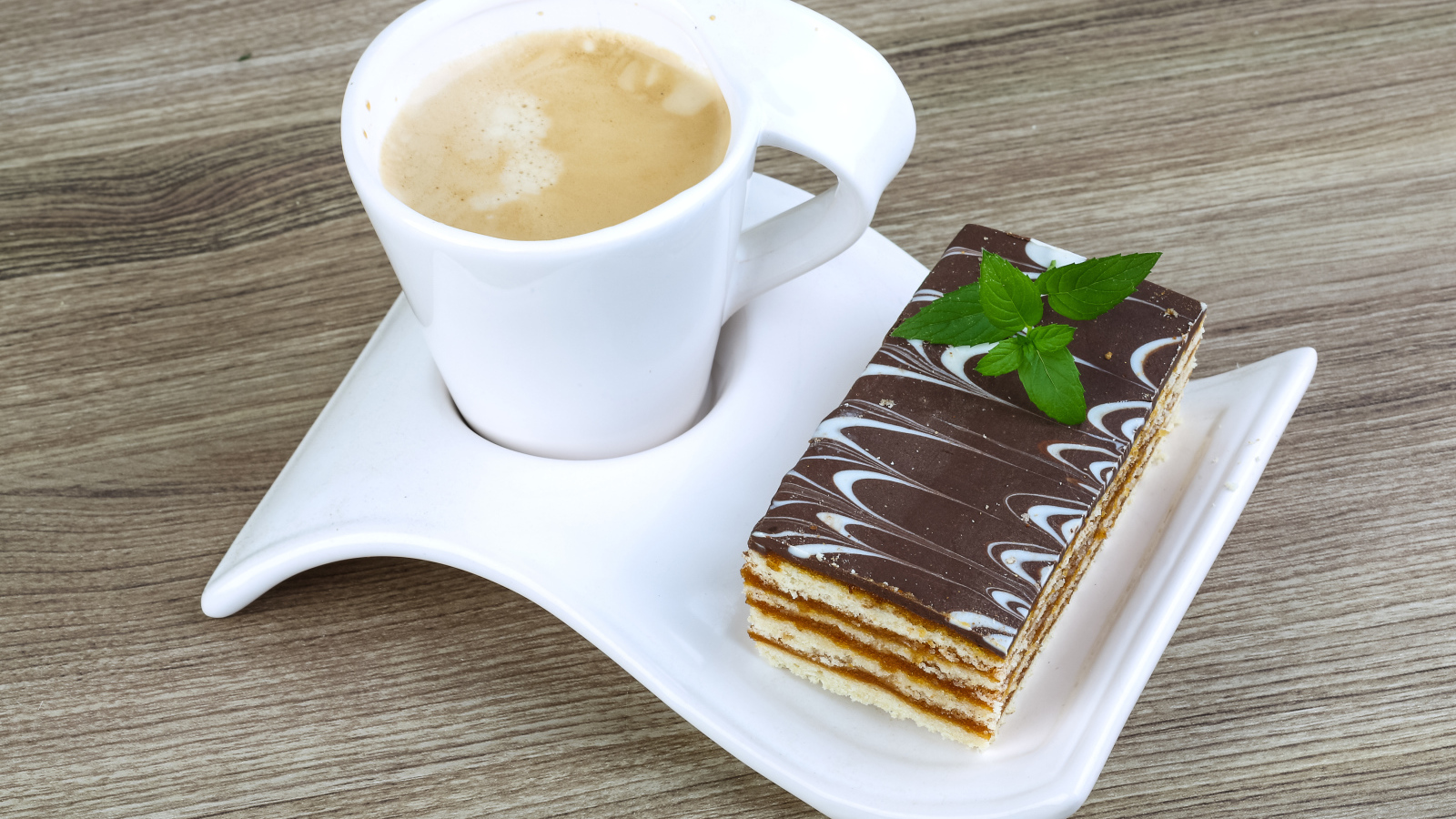 Чашка капучино на тарелке с пирожным 