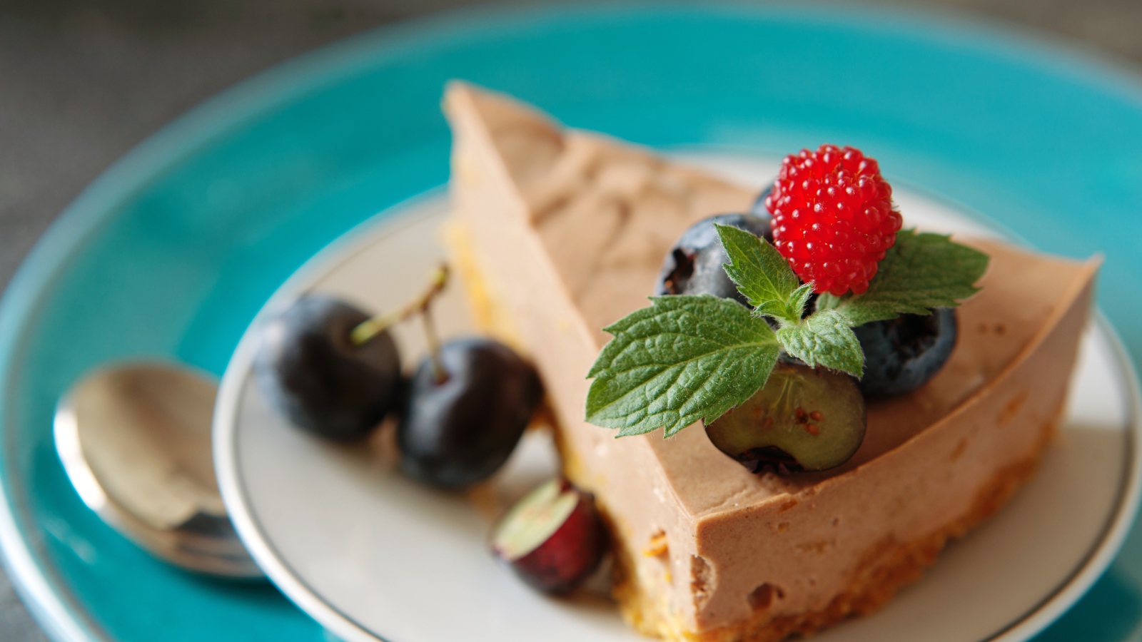 Кусок чизкейка на тарелке с ягодами черники и малиной