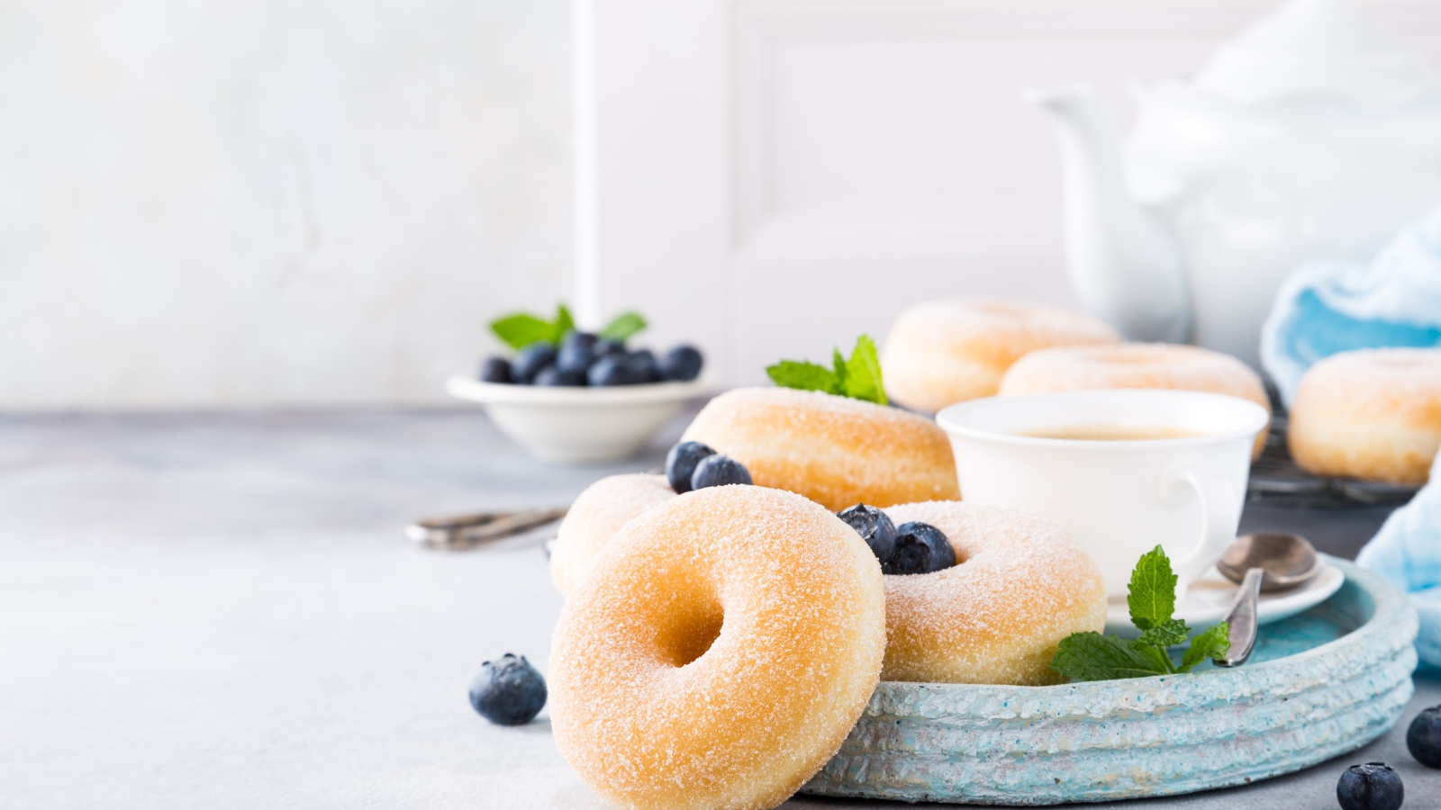 Аппетитные пончики с сахарной пудрой на столе с черникой