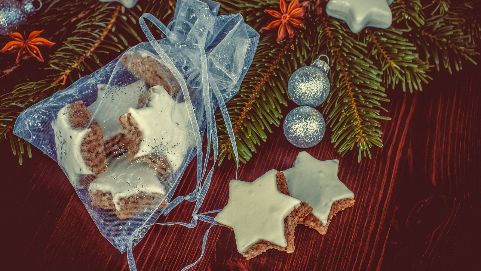 Аппетитное печенье звездочки в мешочке на столе с еловой веткой