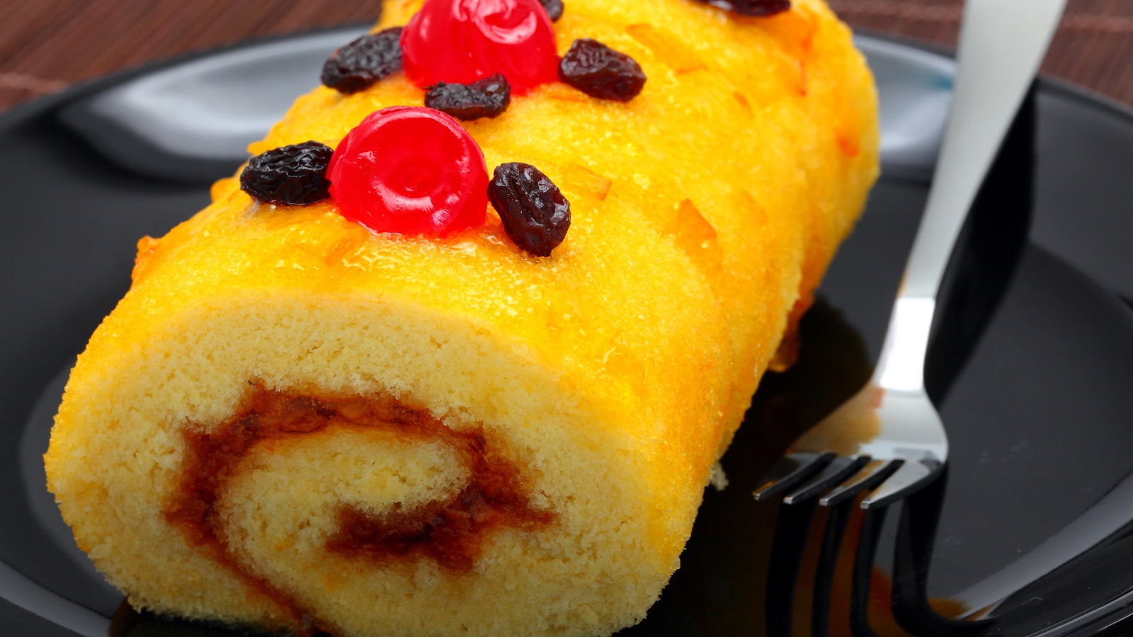 Бисквитный рулет с сухофруктами на тарелке с вилкой