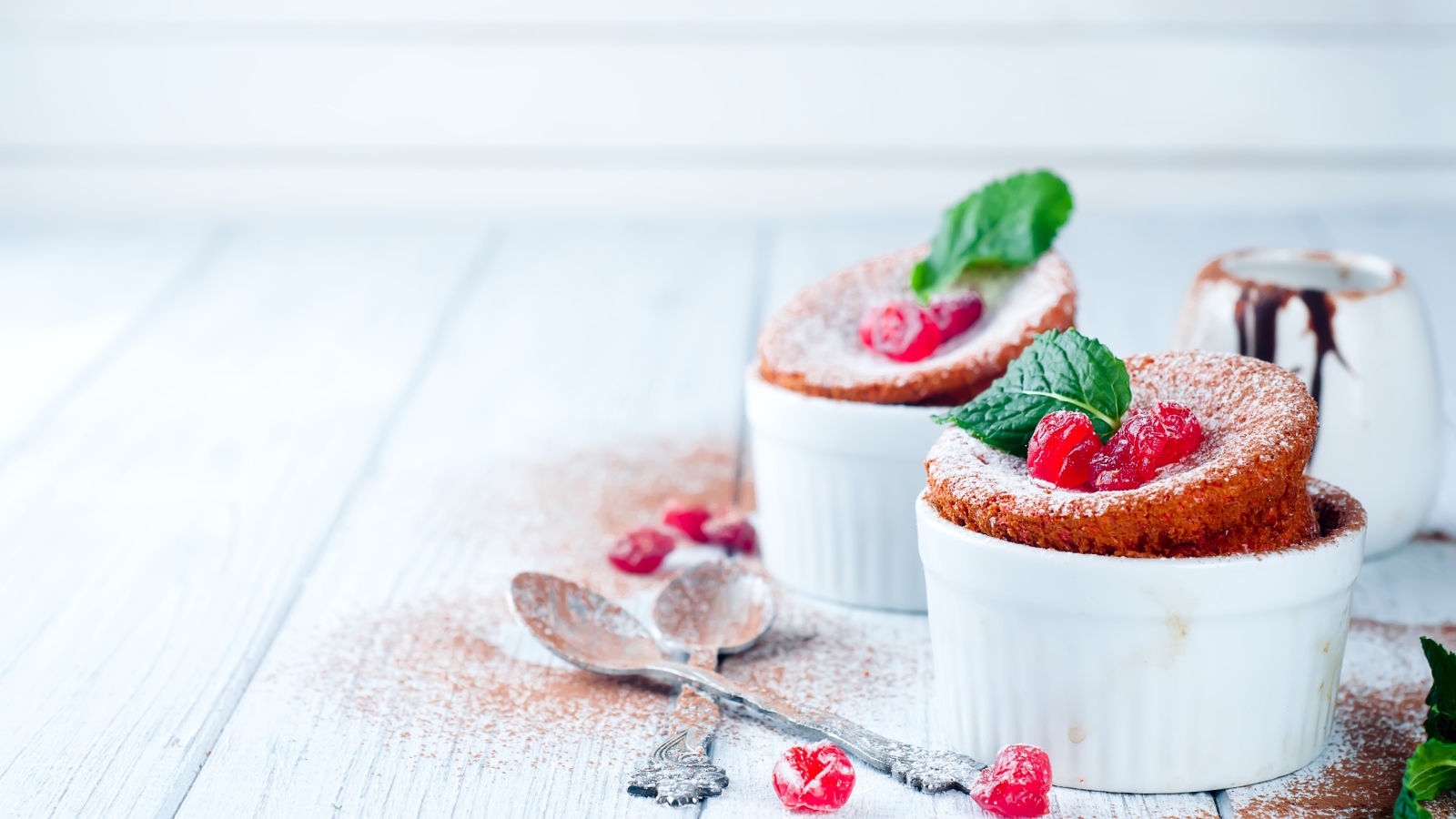 Пирожное с ягодами и сахарной пудрой на столе с ложками