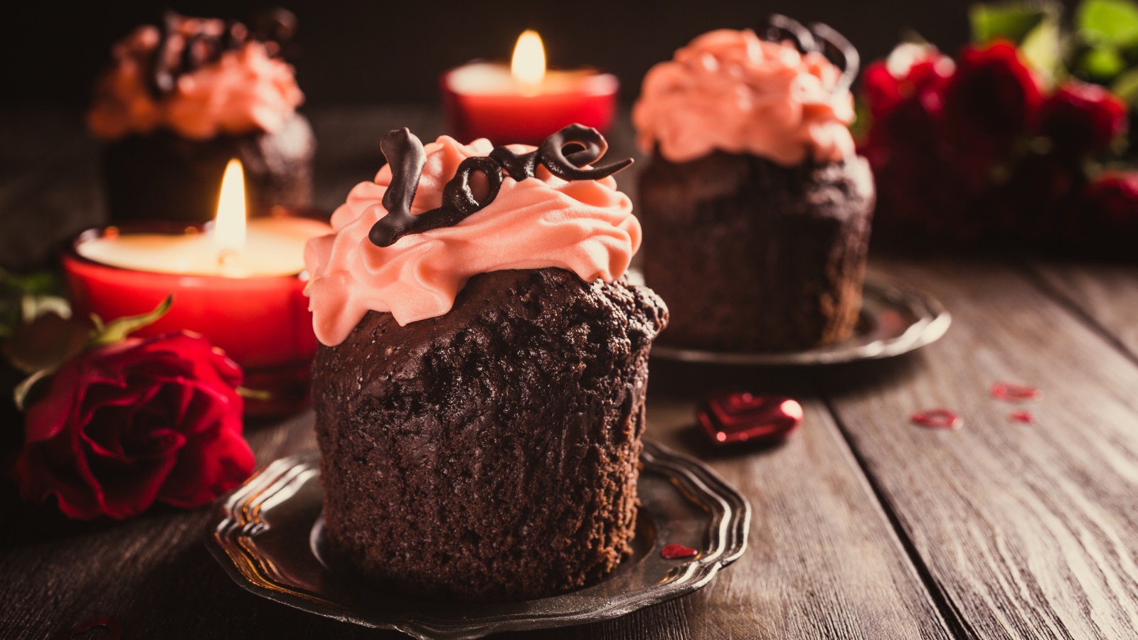 Шоколадные кексы с кремом на столе со свечами и розами