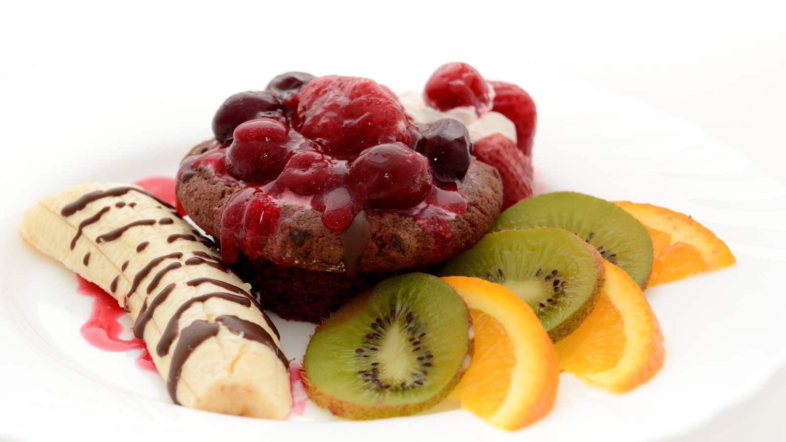 Печенье с вареньем, кусочками банана, киви и апельсина на белом фоне