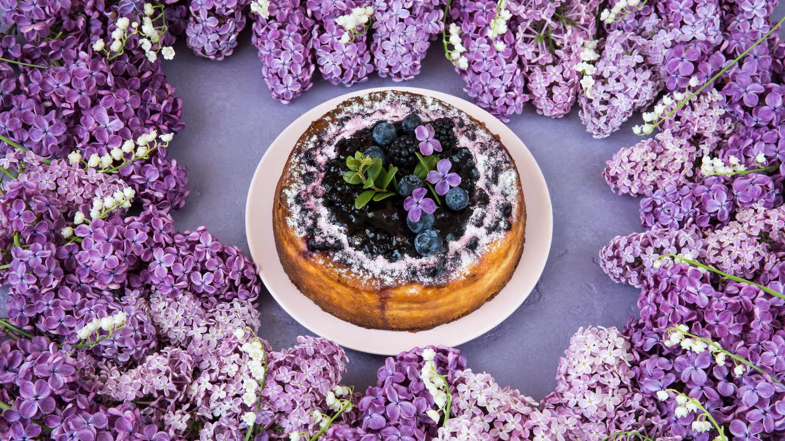 Аппетитный пирог с ягодами на столе с цветами сирени