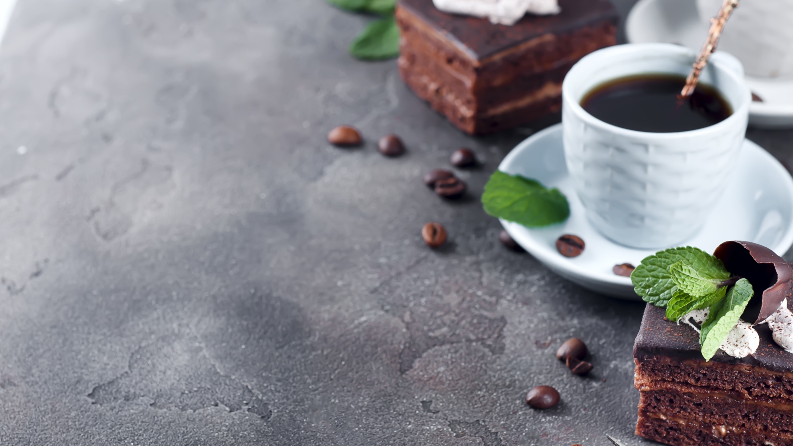 Аппетитное шоколадное пирожное на сером столе с чашкой кофе