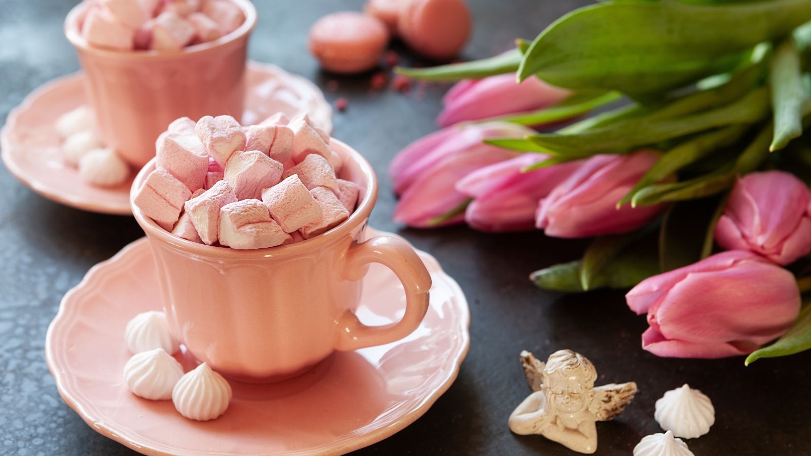 Маршмеллоу в розовой чашке на столе с букетом тюльпанов