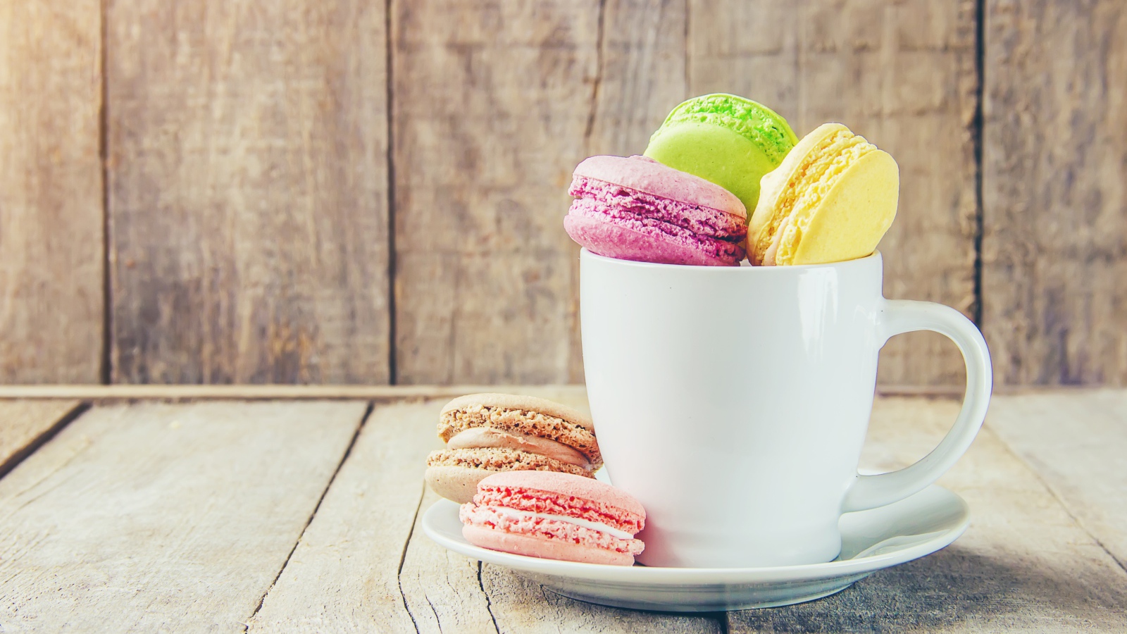 Разноцветный десерт макарон в белой чашке на столе