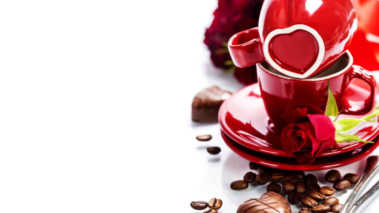 Красные чашки на белом фоне с шоколадными конфетами и кофейными зернами