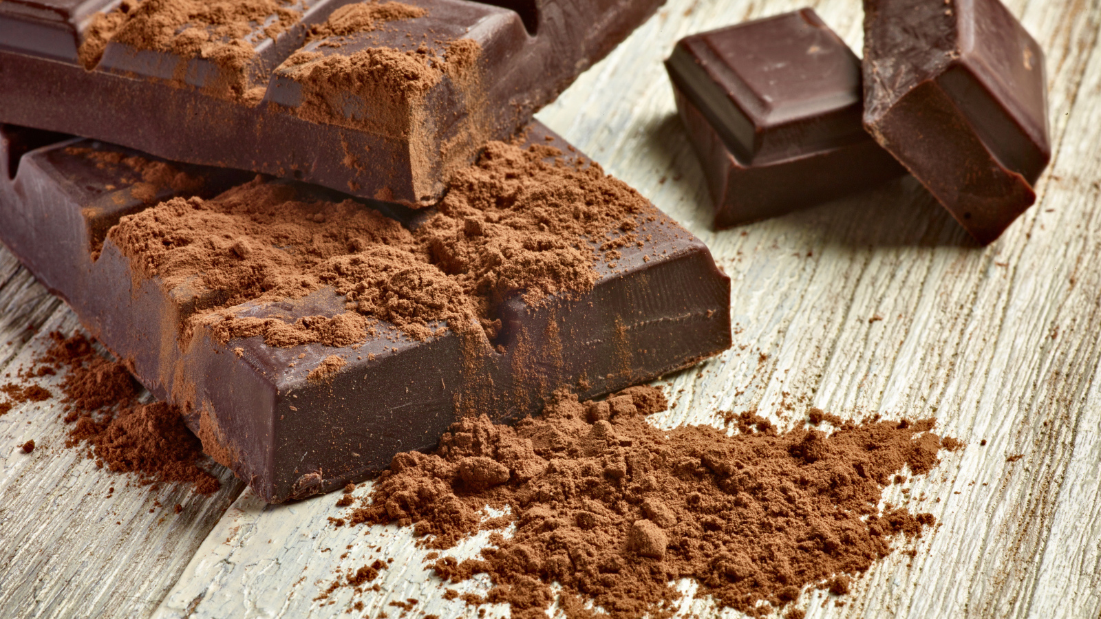 Куски шоколада с какао на деревянном столе 