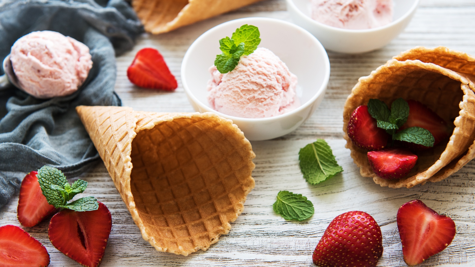 Клубничное мороженое на столе с рожками и клубникой