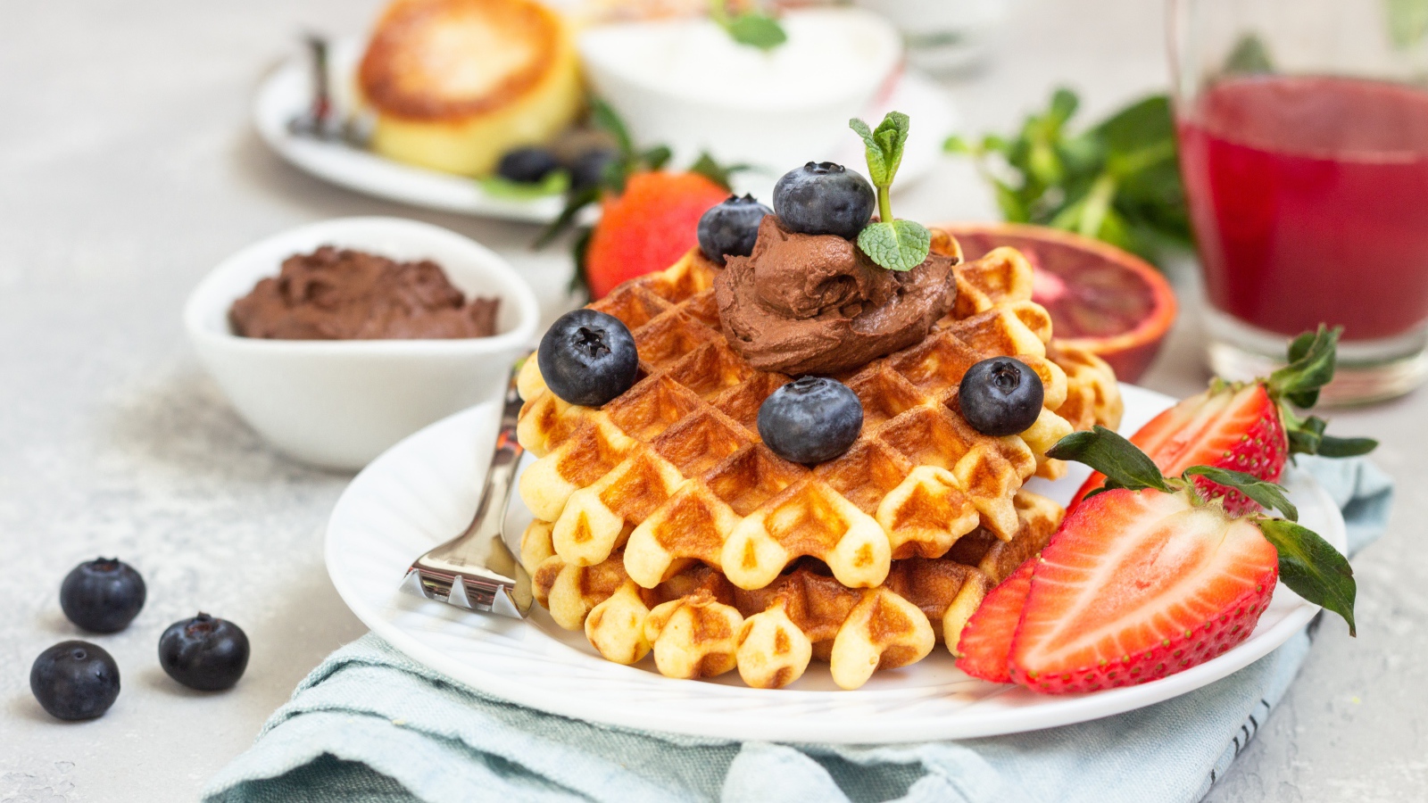 Сладкая вафля с шоколадом, ягодами черники и клубники на тарелке