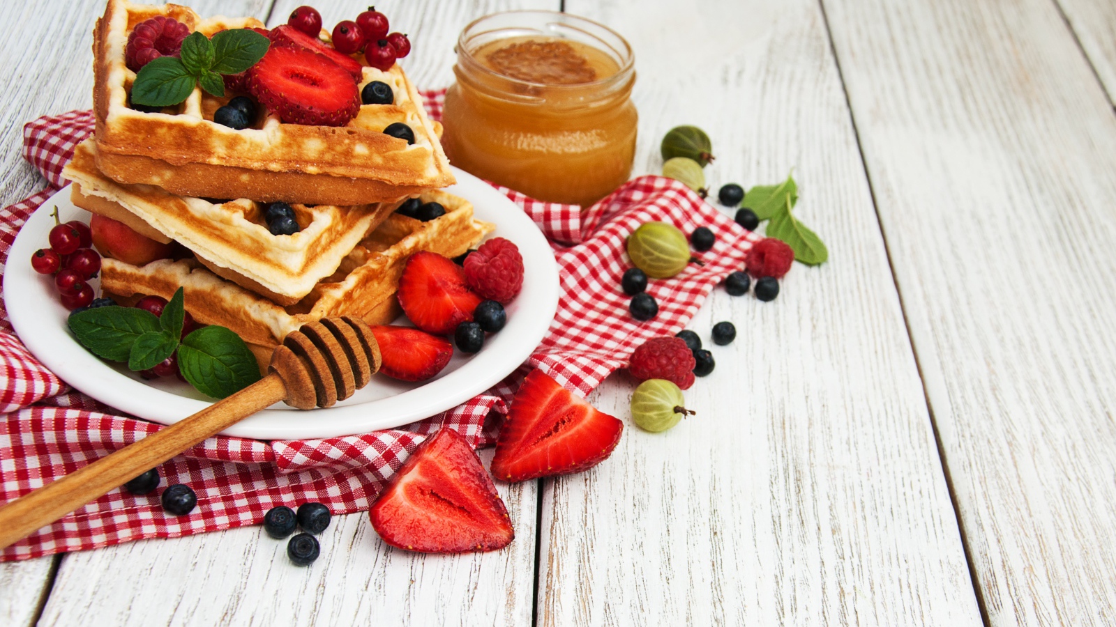 Сладкие вафли на столе с ягодами и медом