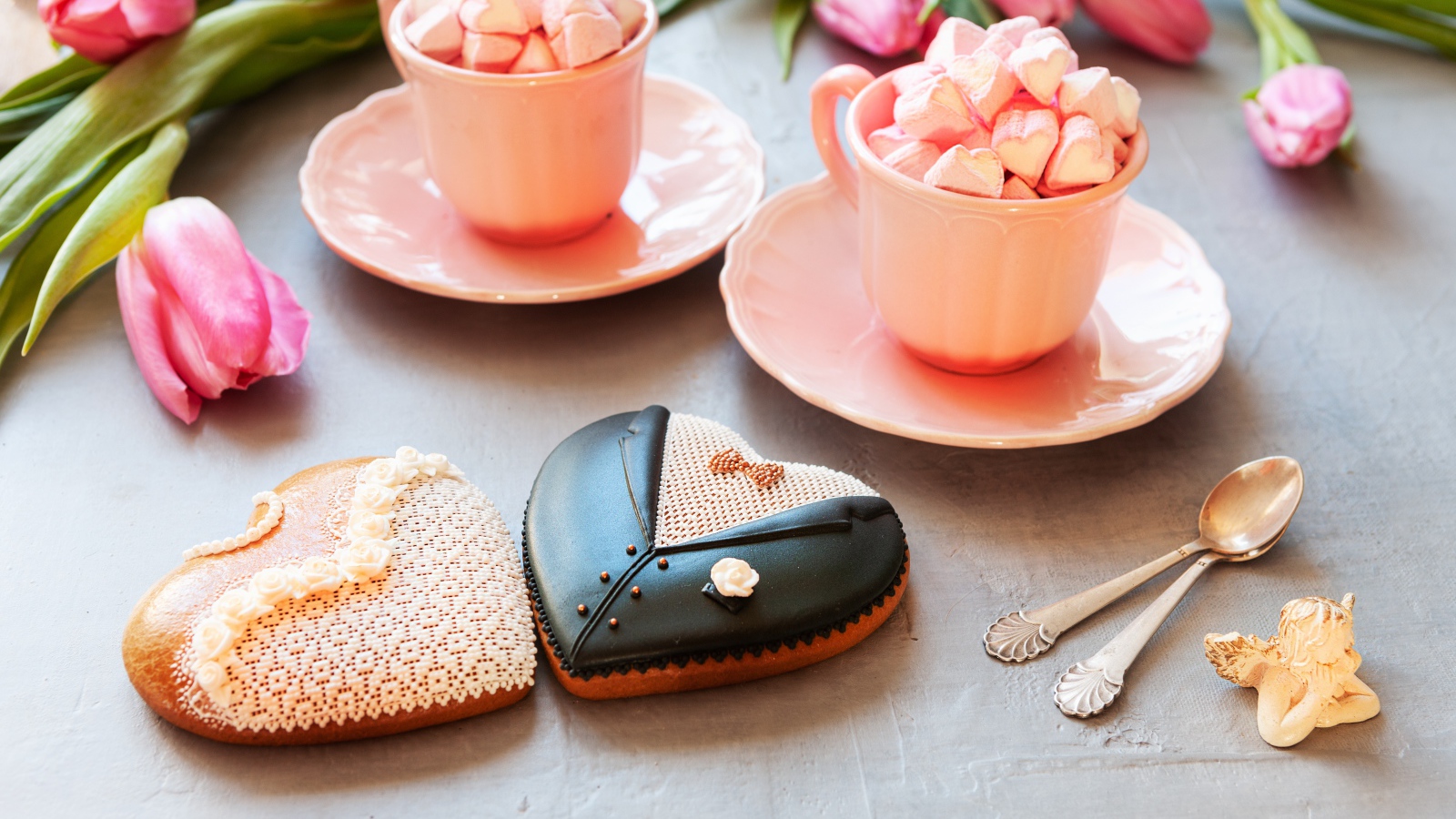 Две розовые чашки с маршмеллоу на сером фоне с печеньем и тюльпанами
