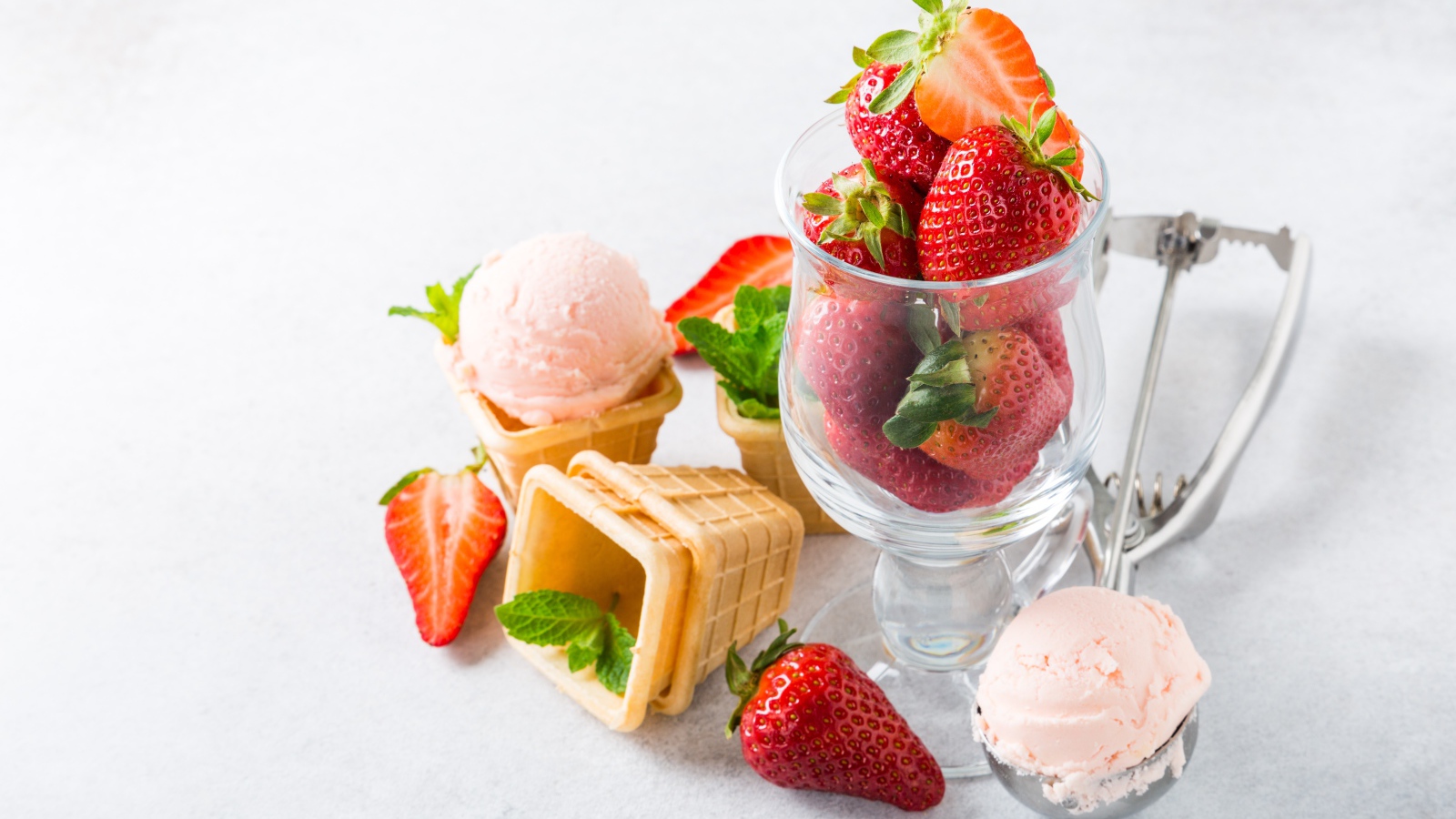 Вафельные стаканчики с мороженым на столе со свежей клубникой