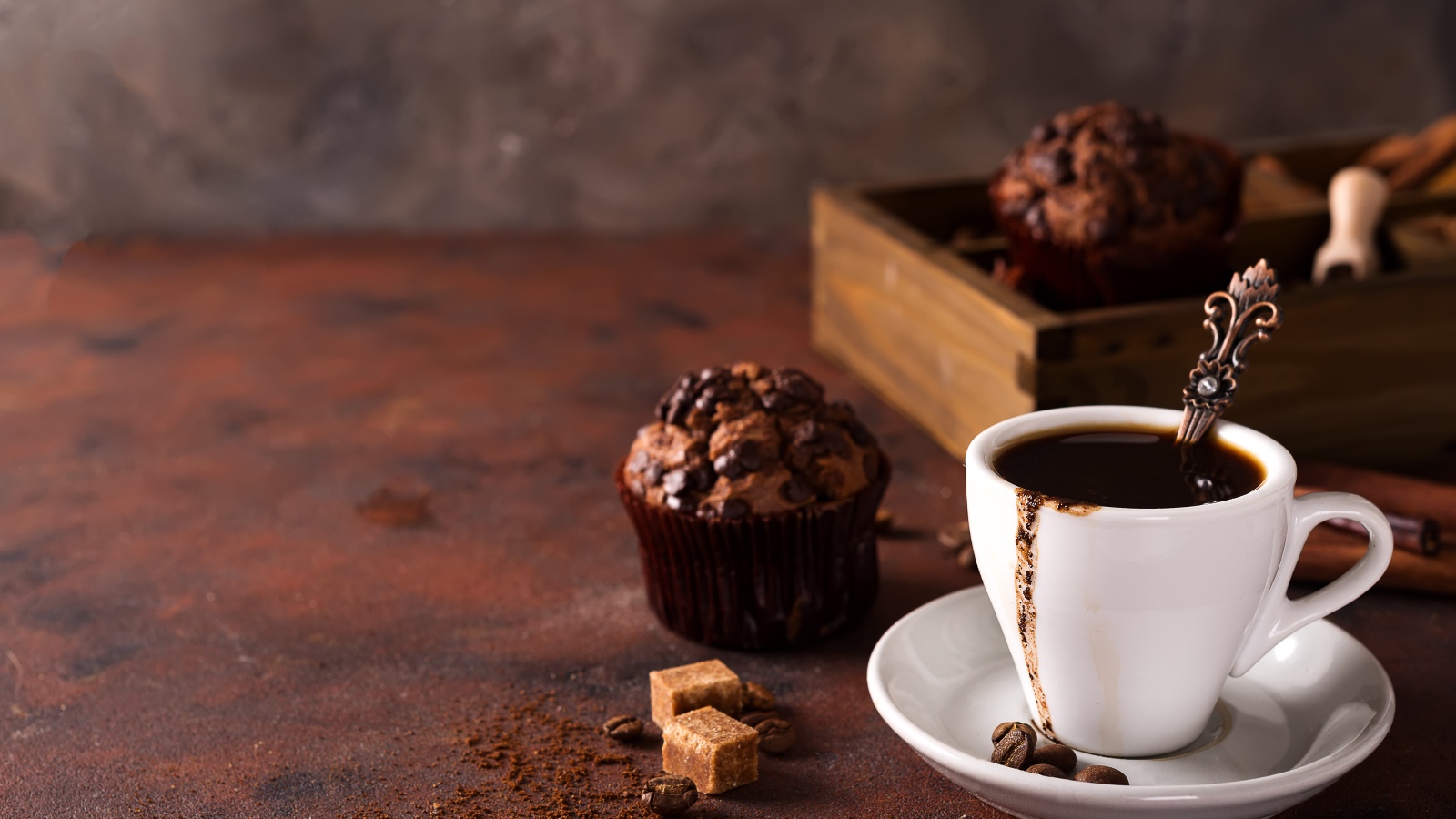 Белая чашка кофе и кекс с шоколадом на столе