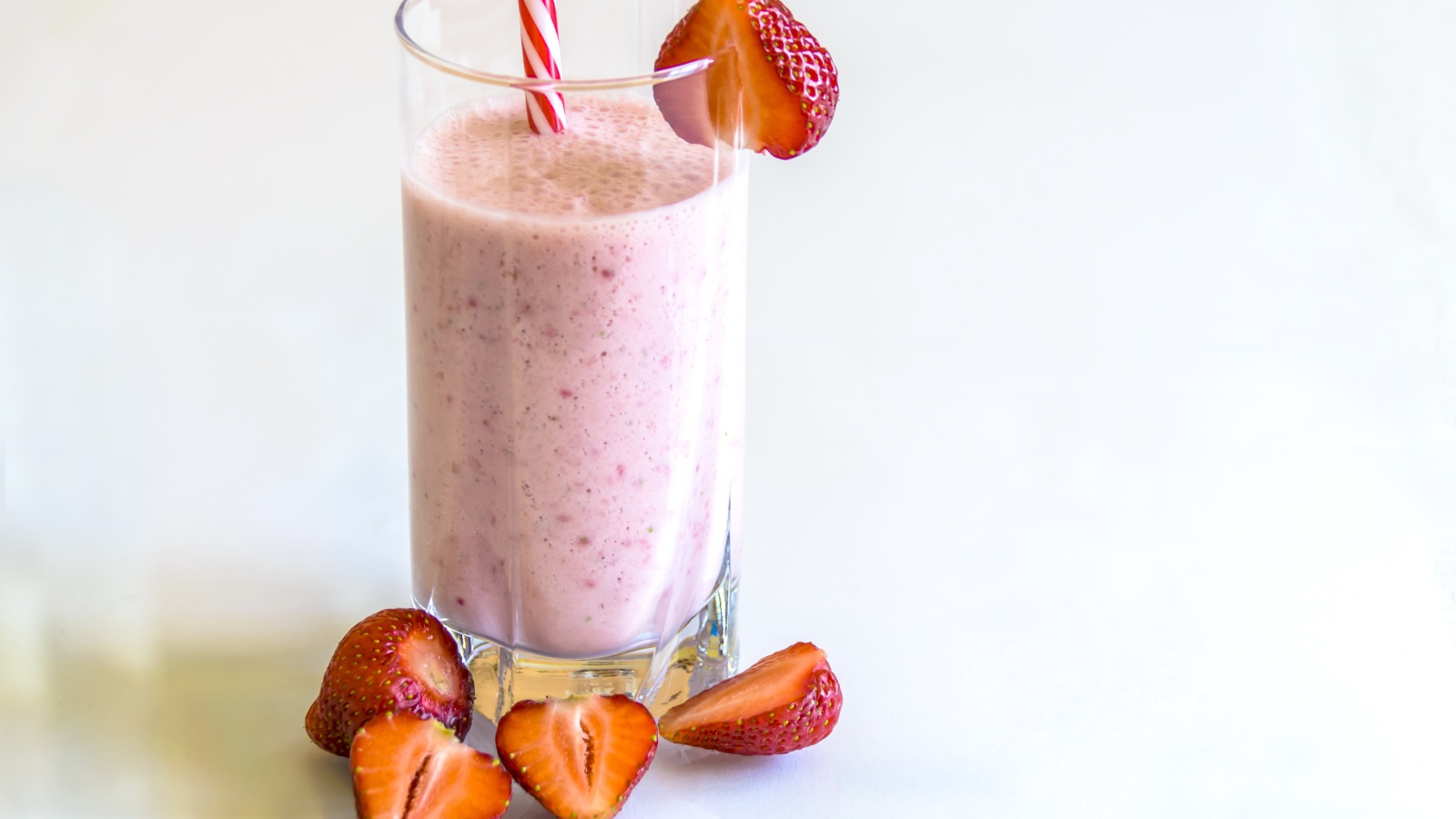 Стакан клубничного смузи на белом фоне с ягодами
