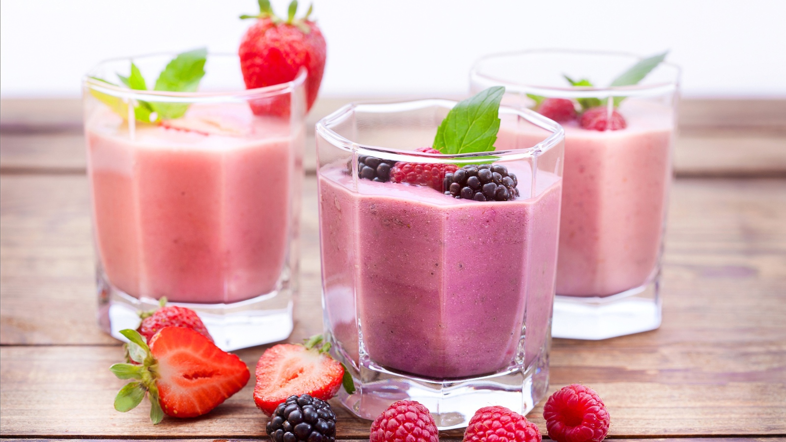 Ягодное смузи в стаканах на столе с ягодами малины, черники и клубники