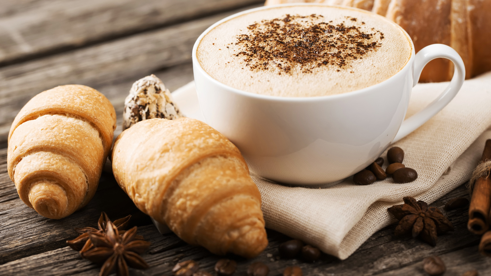 Чашка капучино на столе круассанами