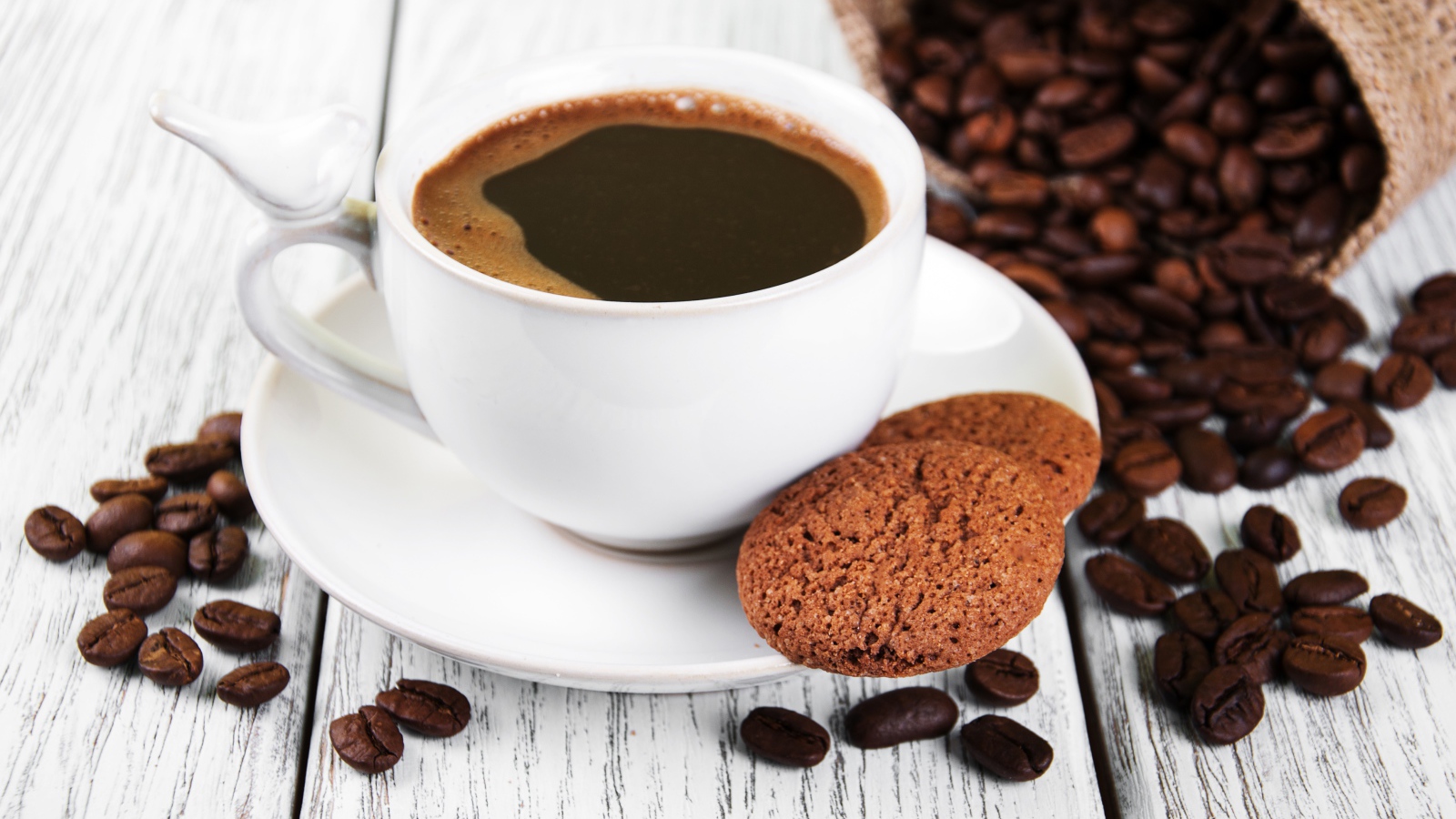 Чашка кофе на столе с кофейными зернами и печеньем