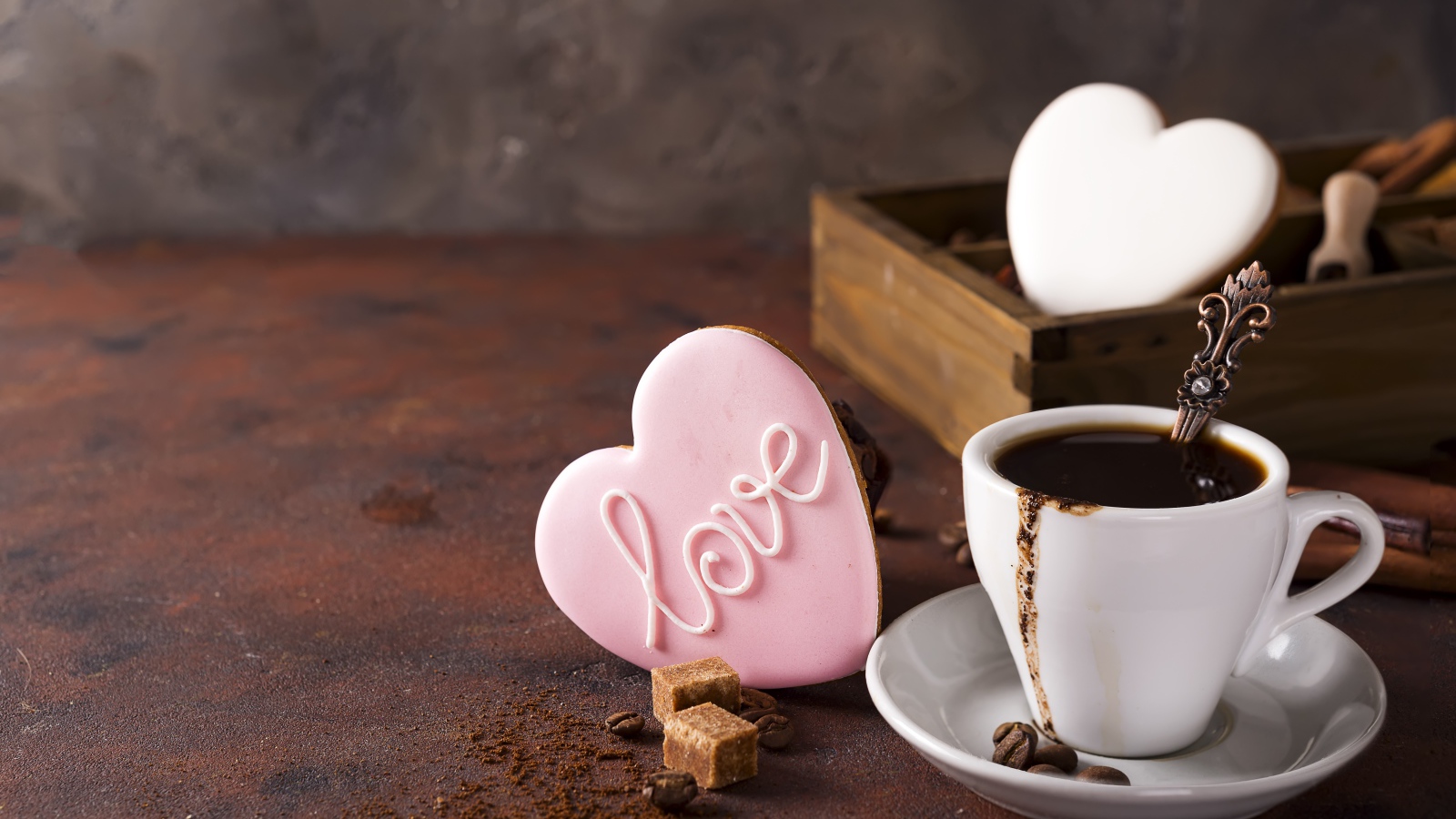 Чашка кофе на столе с сахаром и печеньем в форме сердца 