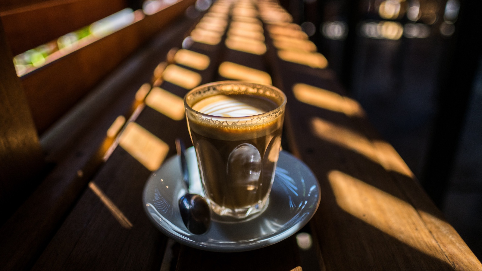 Стакан с кофе стоит на деревянном лавке