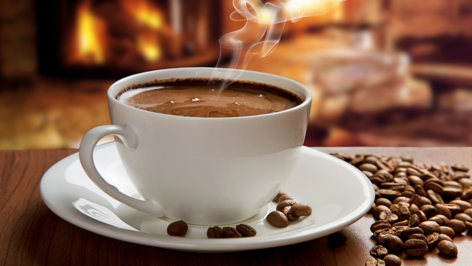 Большая белая чашка с горячим кофе на столе с кофейными зернами