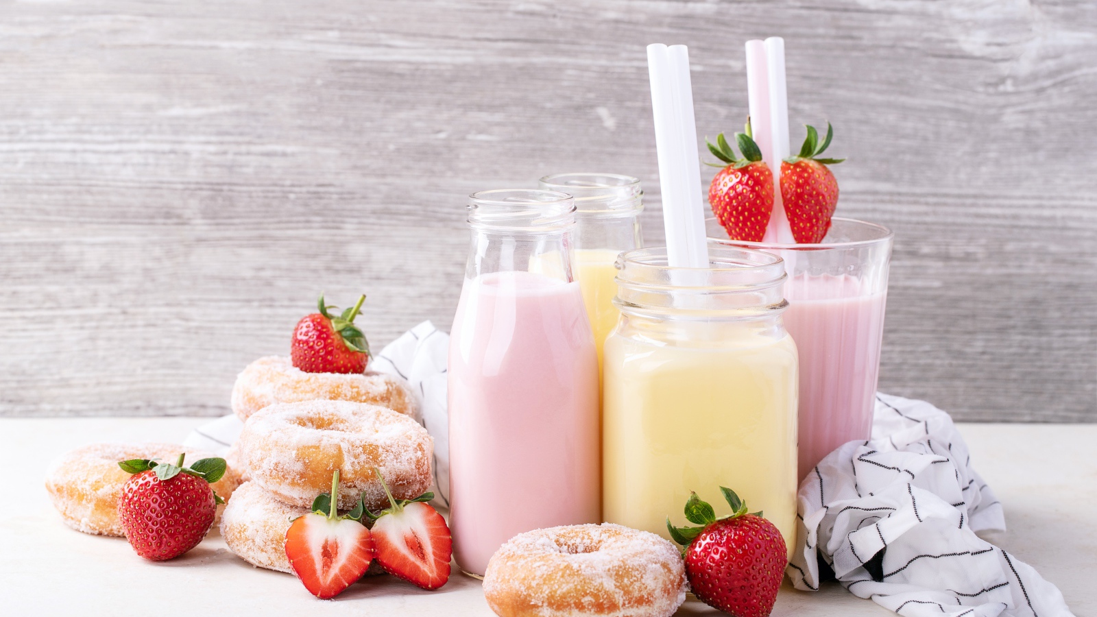 Молочные коктейли на столе с пончиками и ягодами клубники 