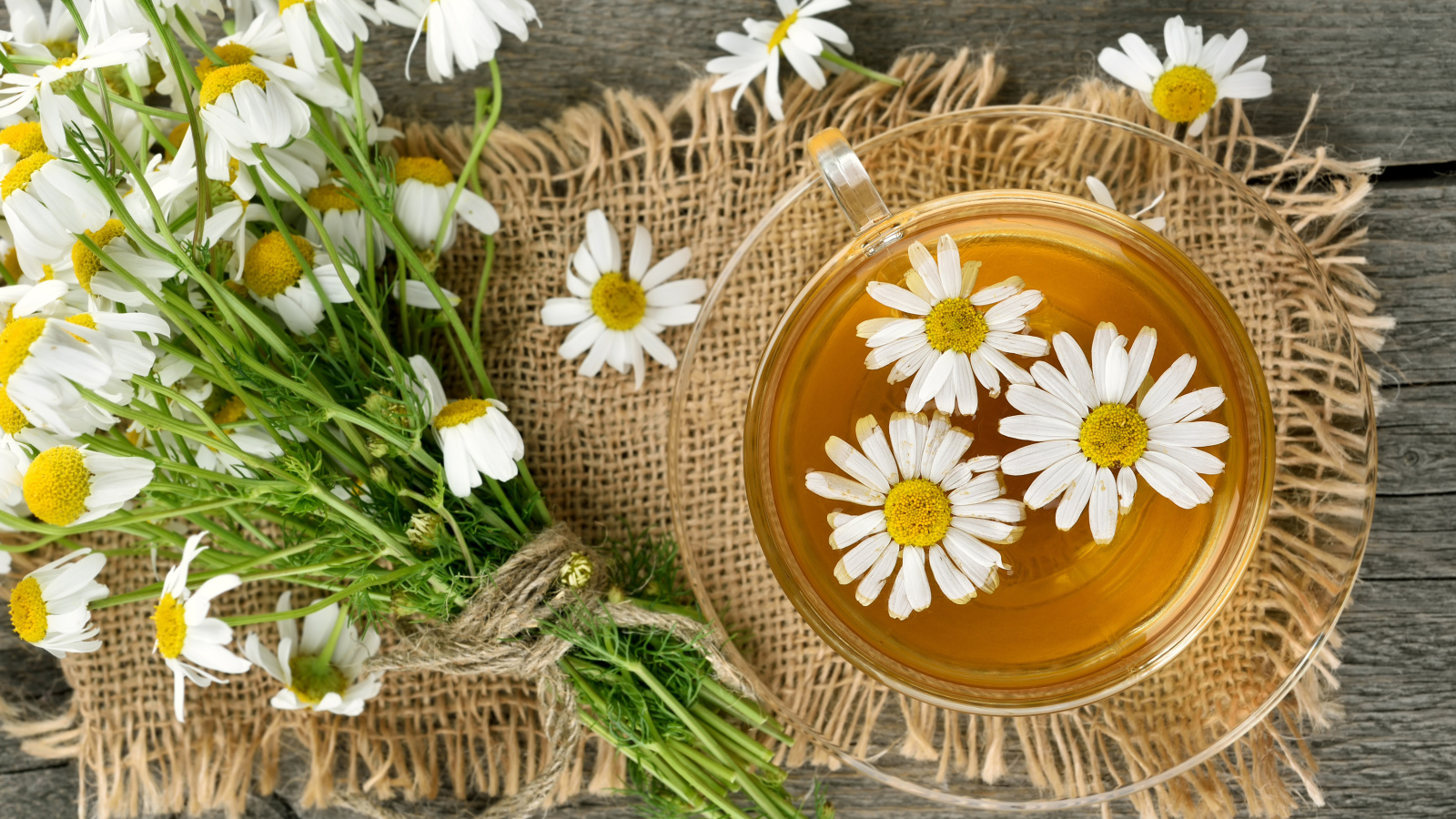 Чай в стеклянной чашке на столе с ромашкой