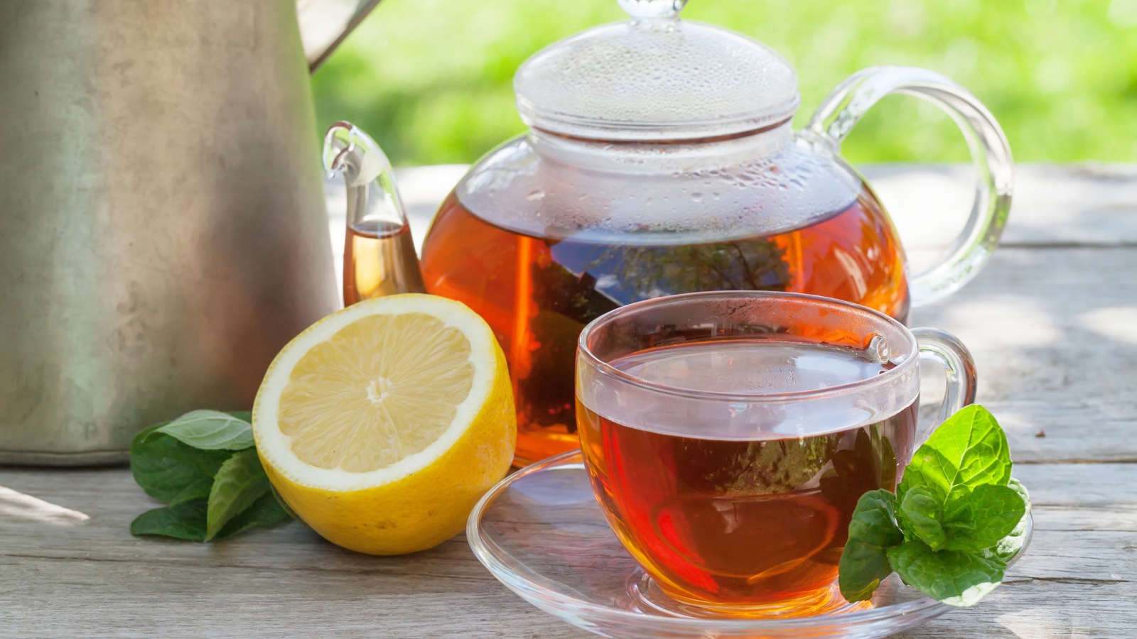 Чайник с чаем на столе с чашкой и половиной лимона