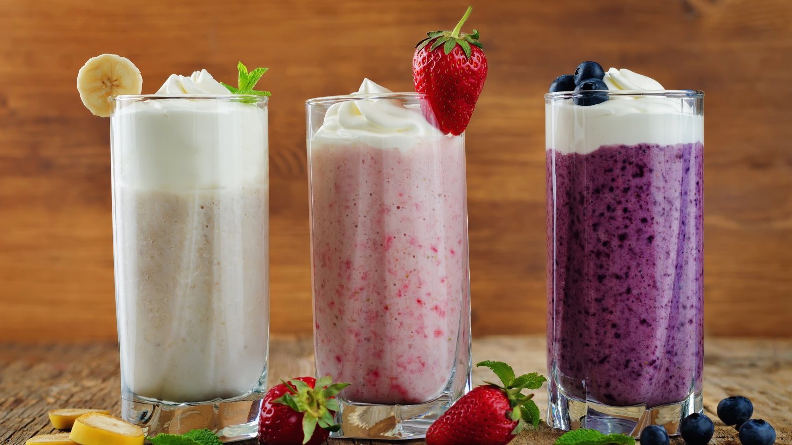 Три стакана смузи со сливками на столе с ягодами