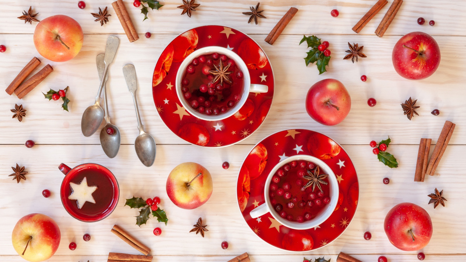 Две чашки клюквенного чая на столе с корицей, яблоками и бадьяном